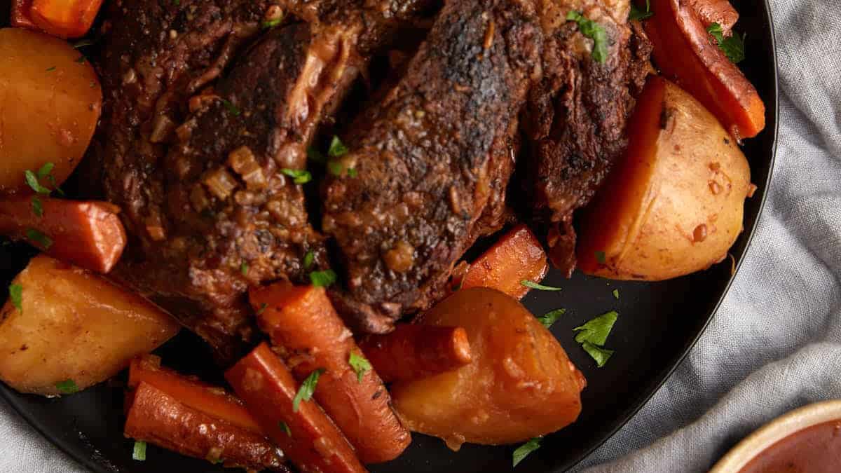A platter of roast beef with carrots and potatoes.