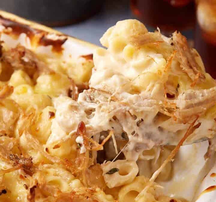 A spoon full of mac and cheese with pulled pork.