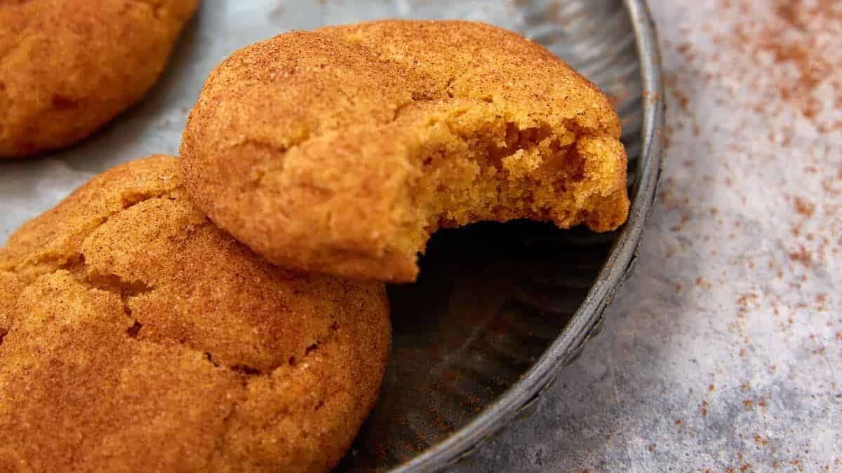 A plate of snickerdoodles with pumpkin with a bite taken out.