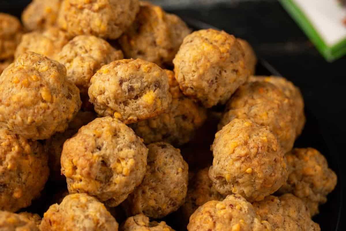 A close-up view of a pile of baked sausage balls with bits of melted cheese visible throughout the browned, textured surface.
