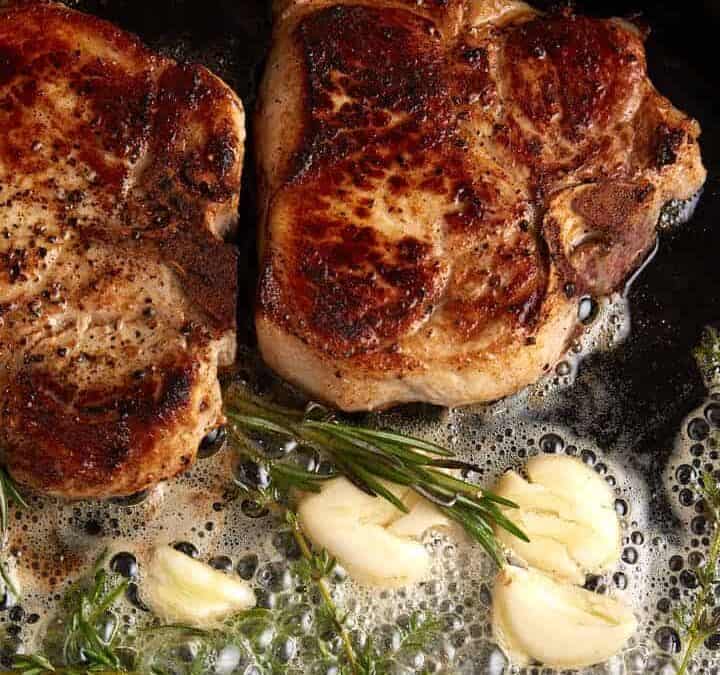 A cast iron skillet with two pork chops.
