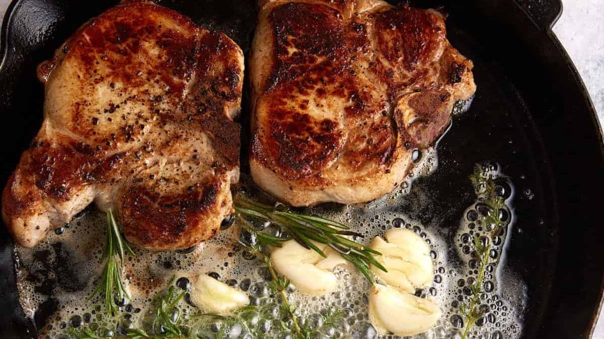 A cast iron skillet with two pork chops.