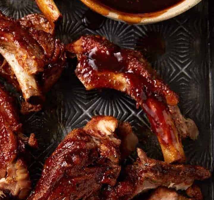 A tray of slow cooker ribs with bbq sauce.
