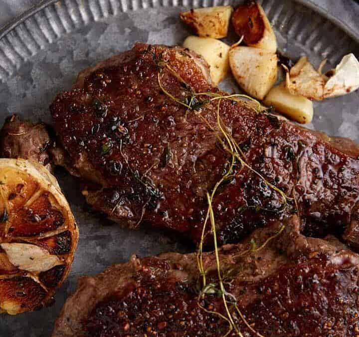 Two skillet cooked steaks on a plate.