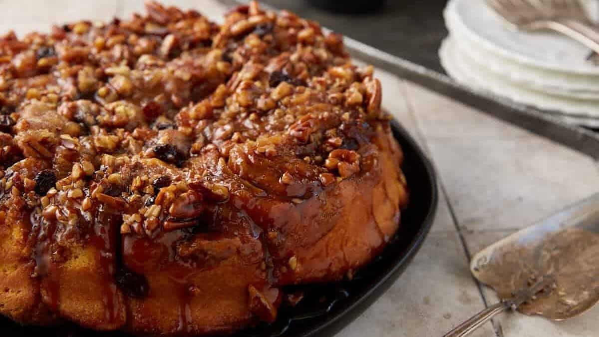 A platter of sticky buns next to some cups.