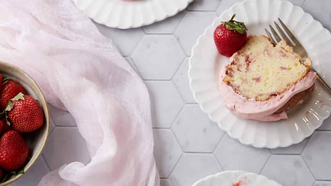 Slices of strawberry bundt cake next to a bowl of strawberries.