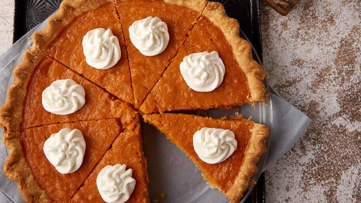 A sliced sweet potato pie topped with whipped cream.