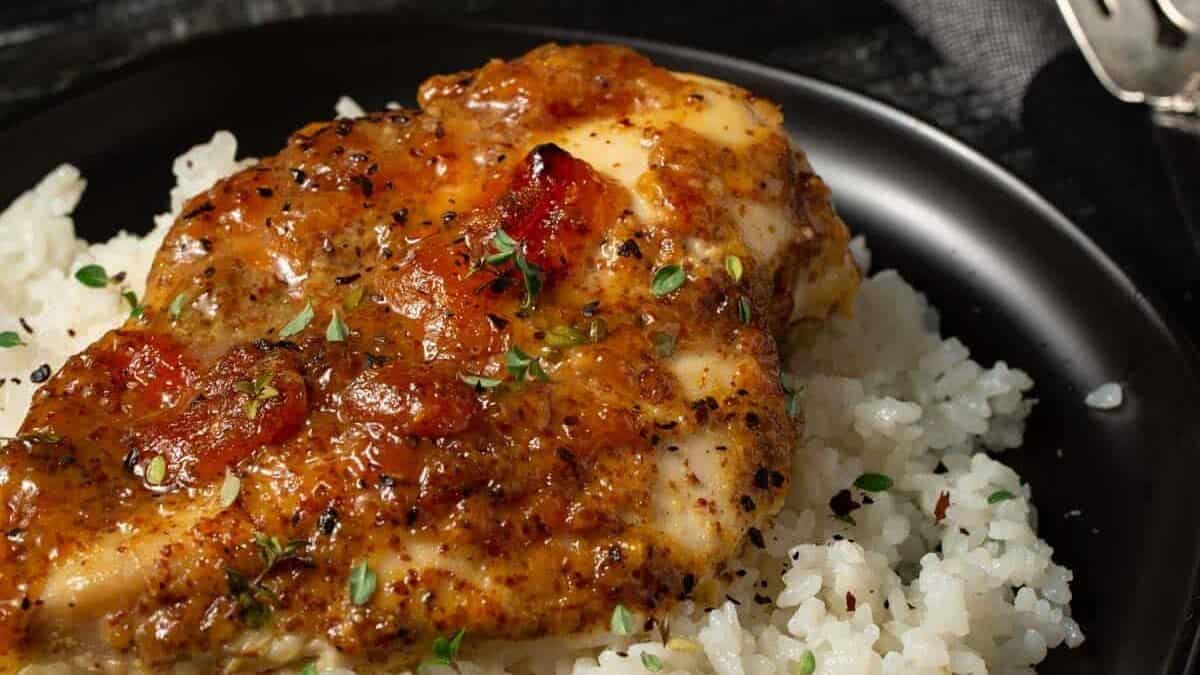 A plate of apricot chicken on a bed of rice.