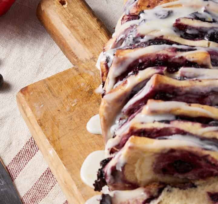 A loaf of blueberry bread on a cutting board.