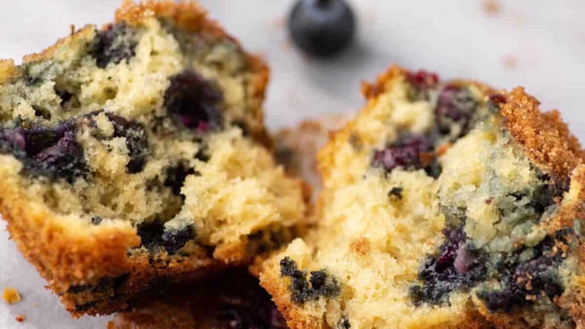 A blueberry muffin split in half on a marble board