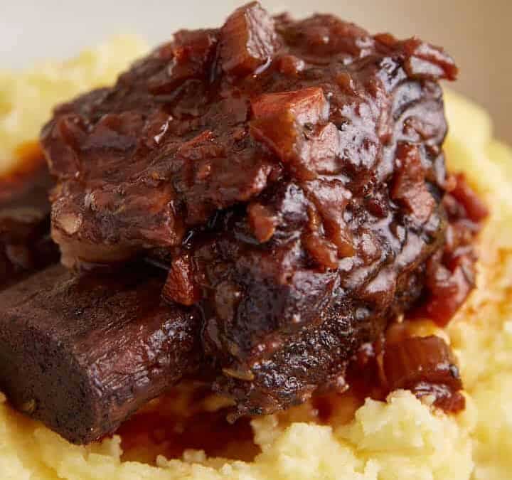 A short rib on a plate covered with sauce.