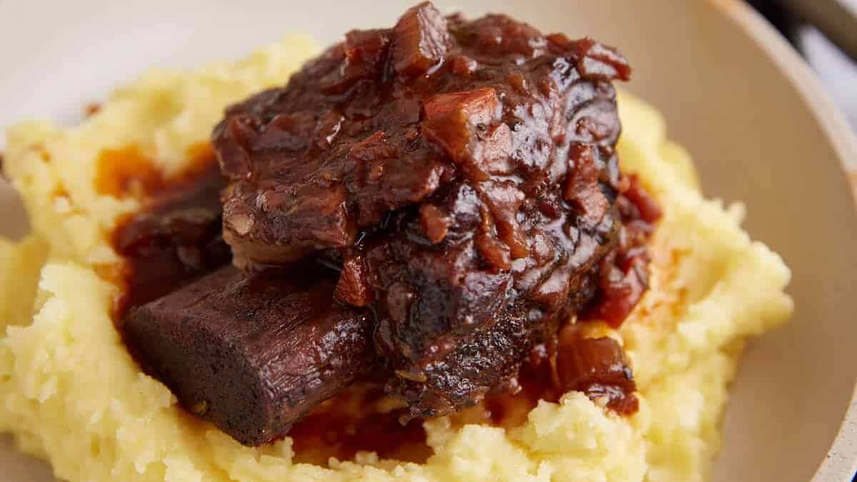A short rib on a plate covered with sauce.