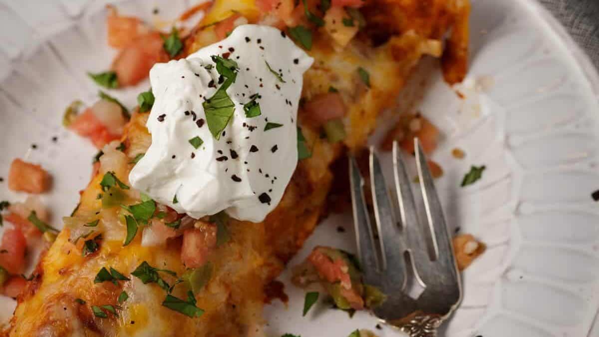 A cheese and chicken enchilada topped with sour cream.