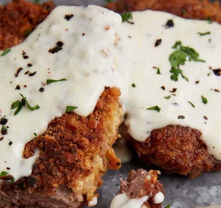 A bite of chicken fried steak on a fork.