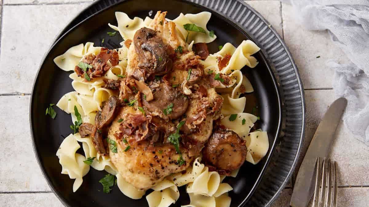 Chicken marsala over egg noodles on a plate.