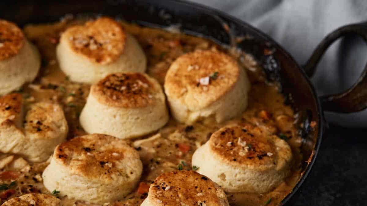 Chicken pot pie in a skillet topped with biscuits.