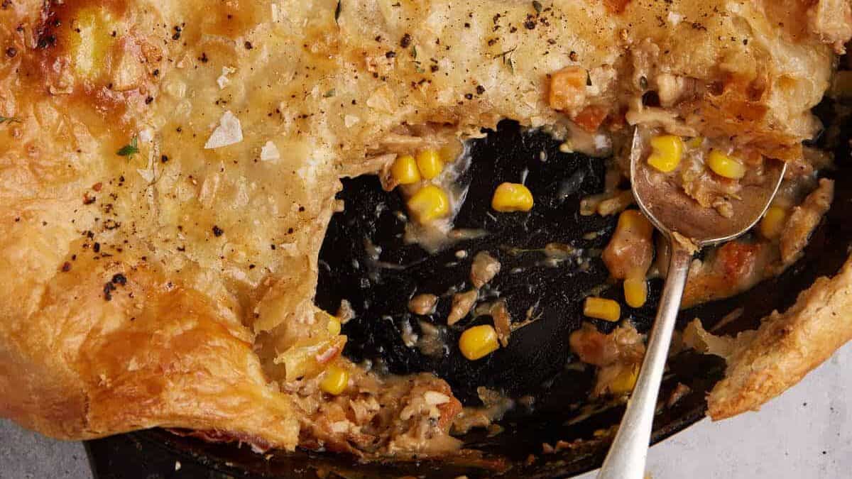 A skillet of chicken pot pie covered with puff pastry.