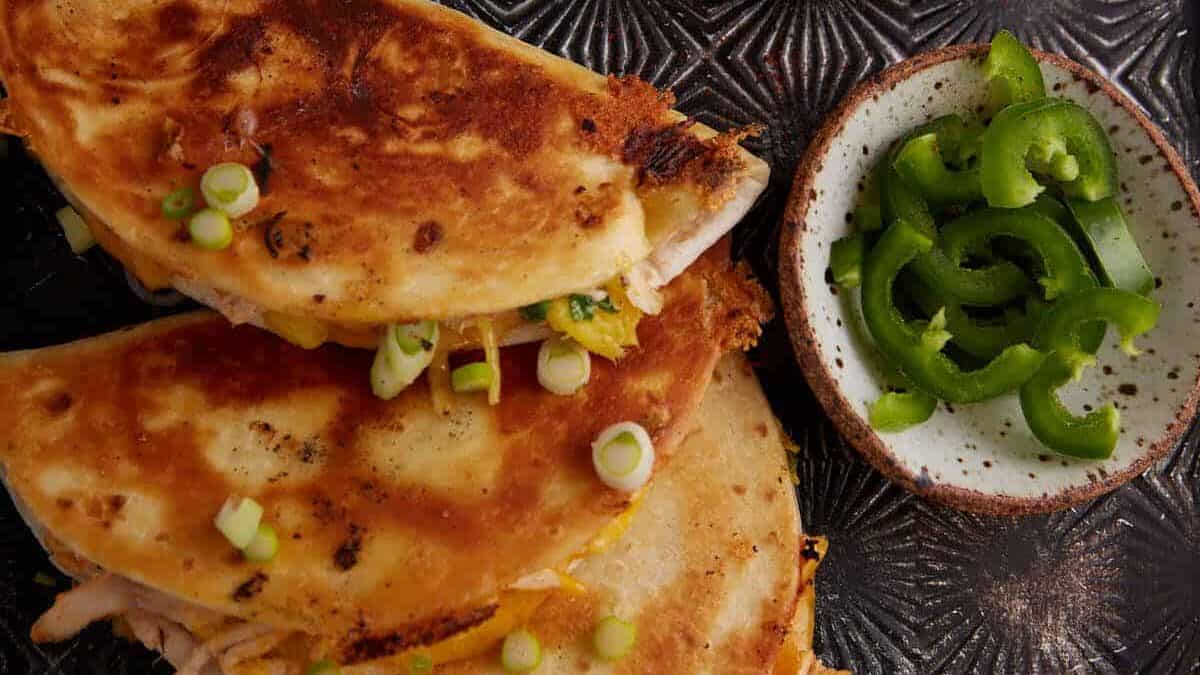 Three quesadillas next to toppings.