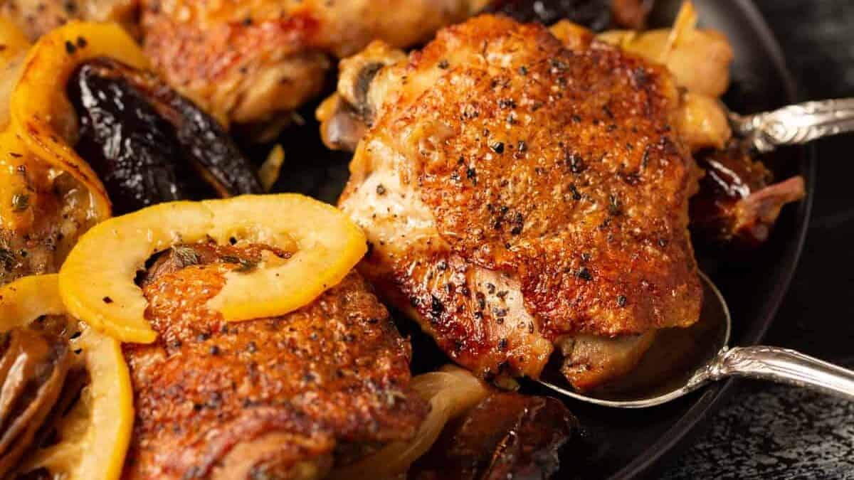 A baked chicken breast being removed from a serving platter.