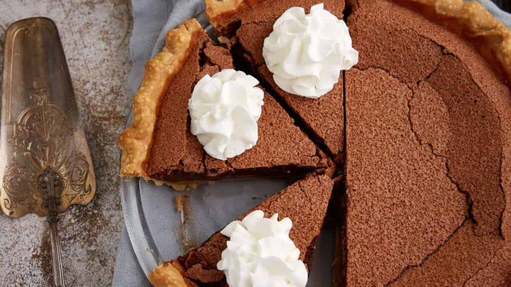 A chocolate chess pie topped with whip cream swirls.