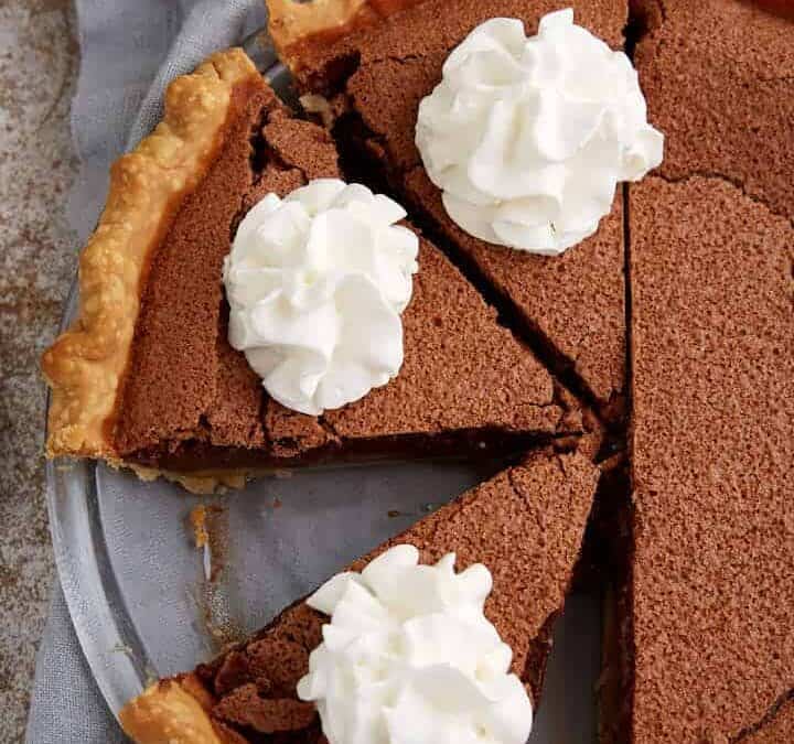 A chocolate chess pie topped with whip cream swirls.