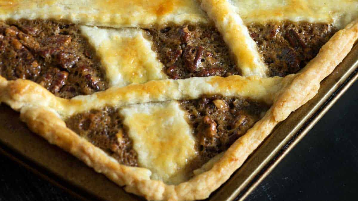 A baked pecan slab pie with criss crossed strips on top.