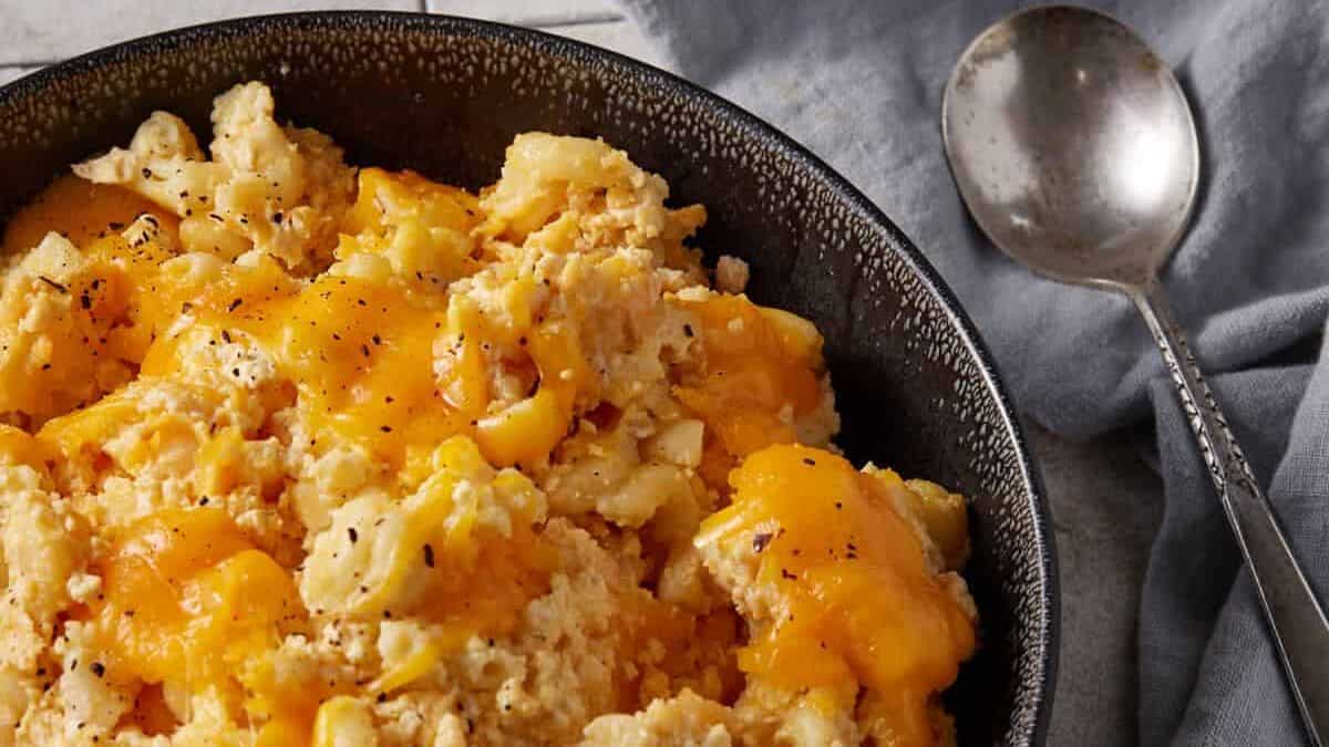 A bowl of crock pot mac n cheese in a bowl next to a spoon.