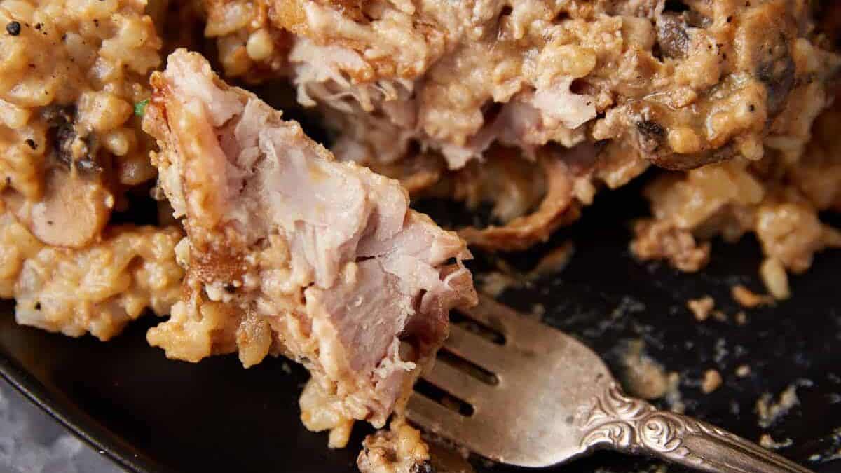 A fork with a bite of slow cooker pork chops.