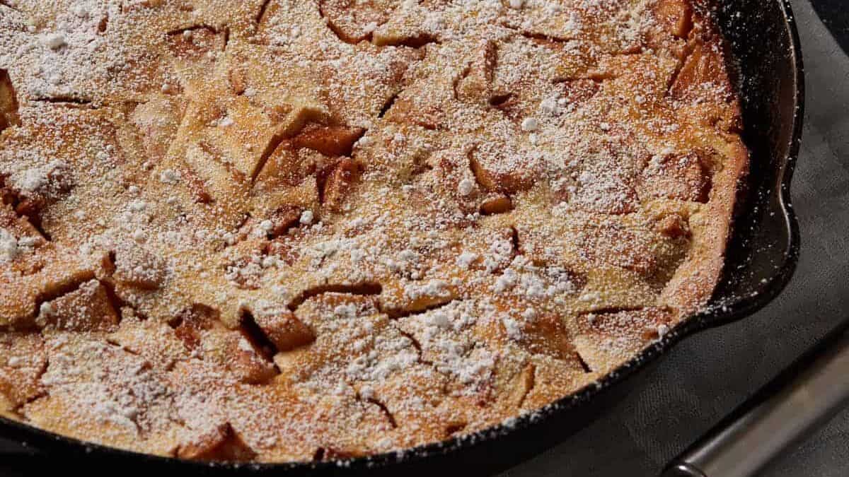 A baked apple pancake covered with powdered sugar.