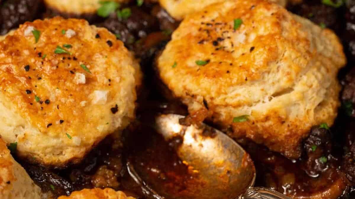 A spoon in the skillet dishing out a serving of Guinness beef pie.