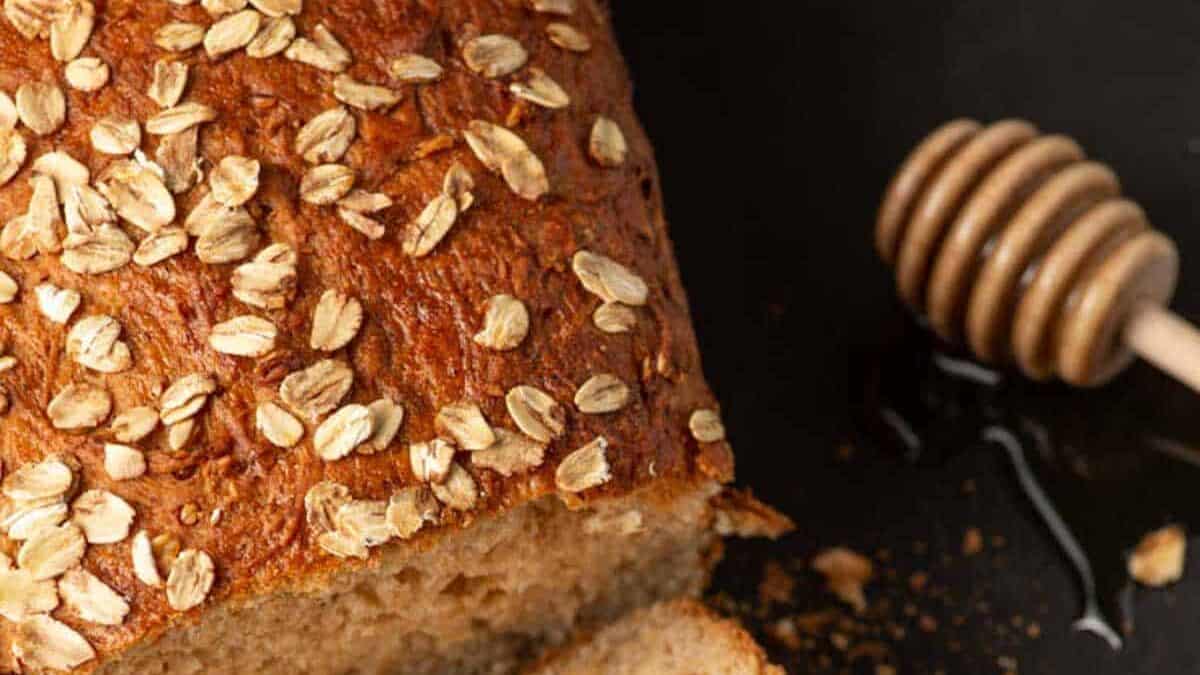 Oatmeal bread sliced with honey on the side.
