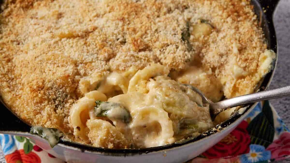 A spoon full of baked mac and cheese with spinach.