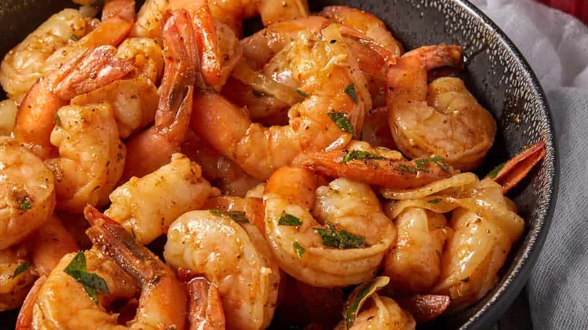 A black bowl of shrimp next to a bowl of lemons.
