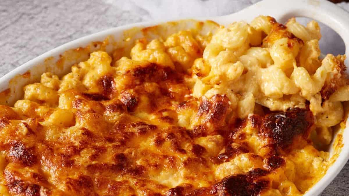 A serving of mac and cheese being removed from a casserole dish.