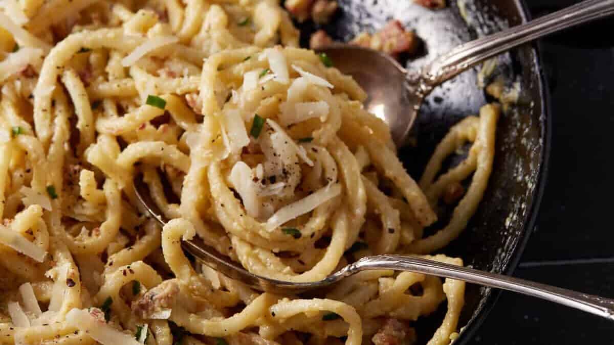 Two serving spoons in a platter of pasta.