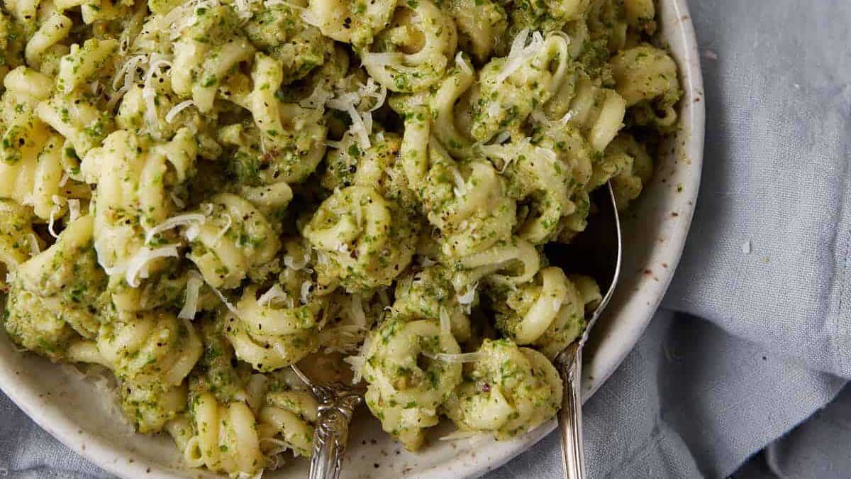 Parsley pesto pasta in a bowl with serving spoons.
