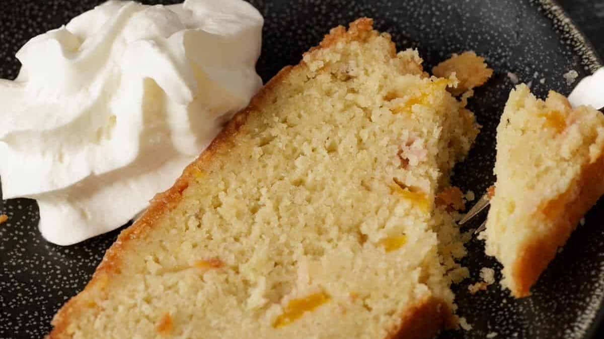 A slice of peach pound cake with whipped cream.