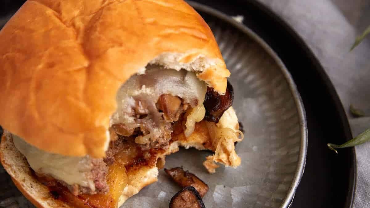 A burger with a bite taken out on a plate.