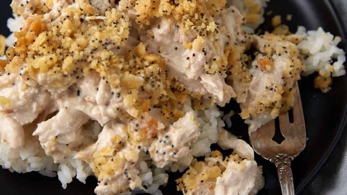 A plate of rice covered with poppy seed chicken.