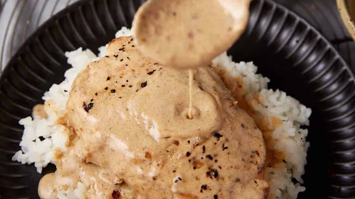 A spoon pouring gravy over pork chops.