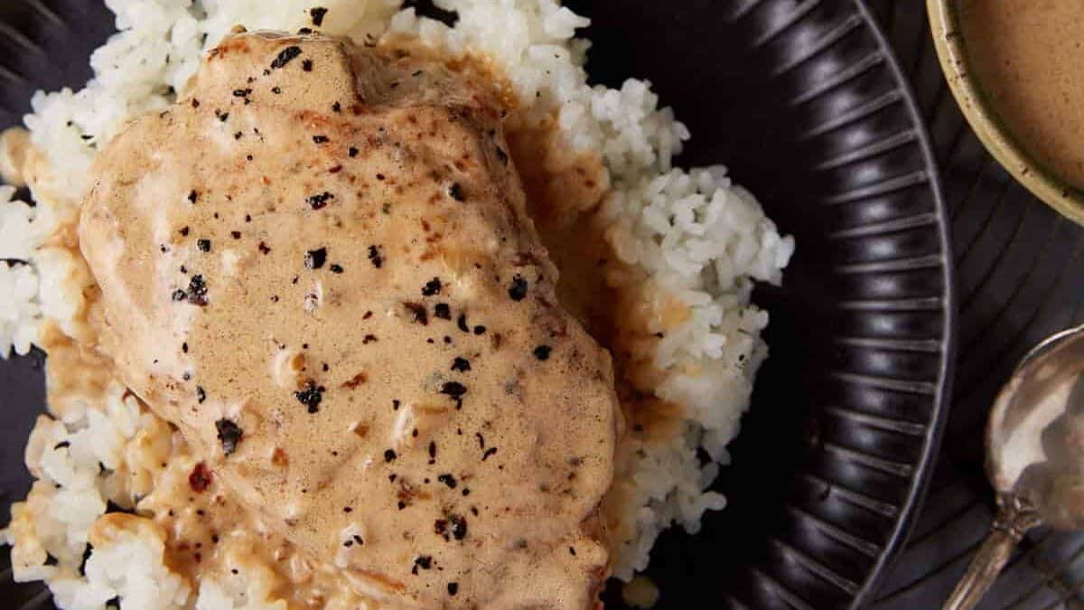 A plate with a pork chop over rice.