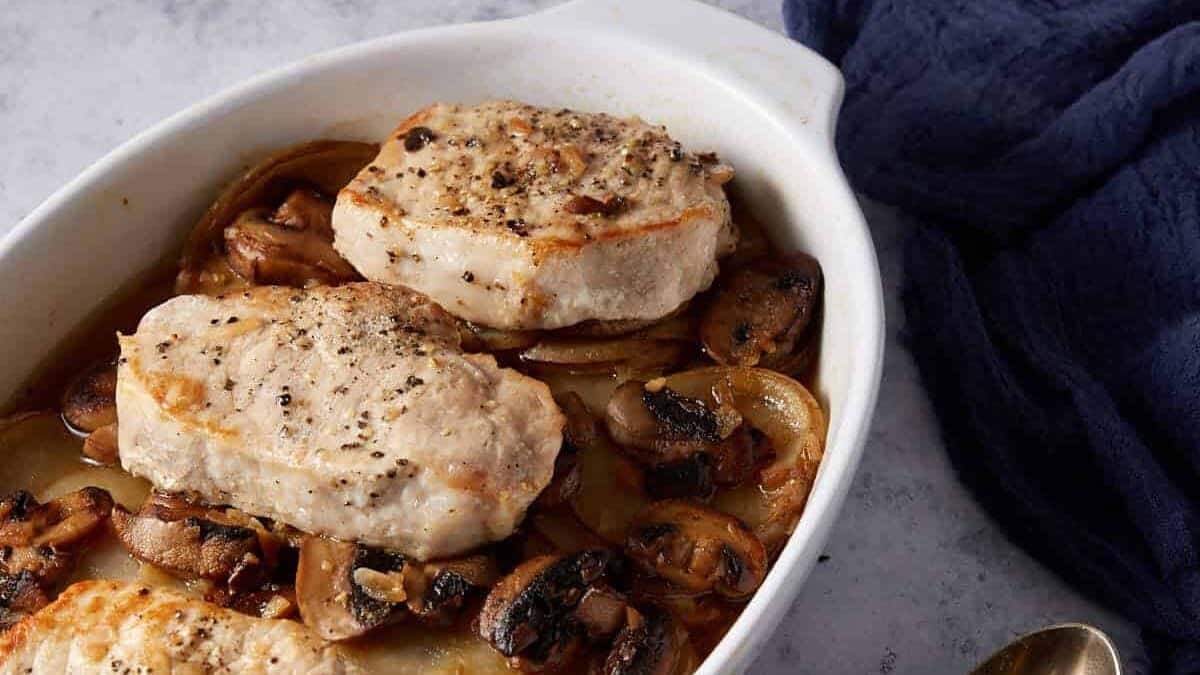 Baked pork chops in a white baking dish.