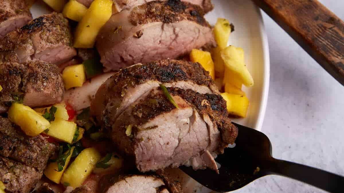 Sliced grilled pork tenderloin served on a wooden cutting board.