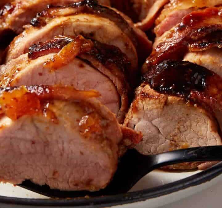 A black fork with a slice of pork tenderloin on top.