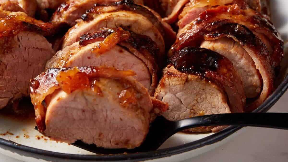 A black fork with a slice of pork tenderloin on top.