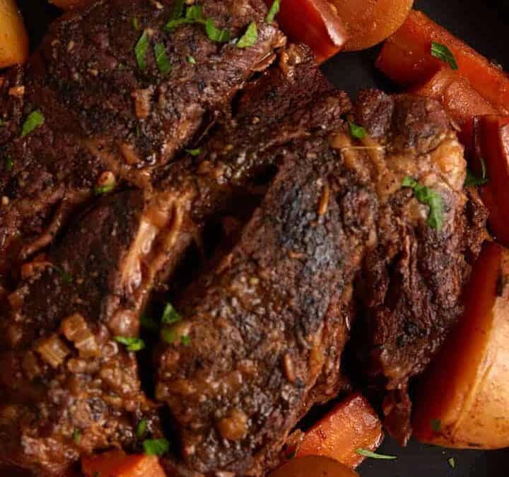 A platter of roast beef with carrots and potatoes.