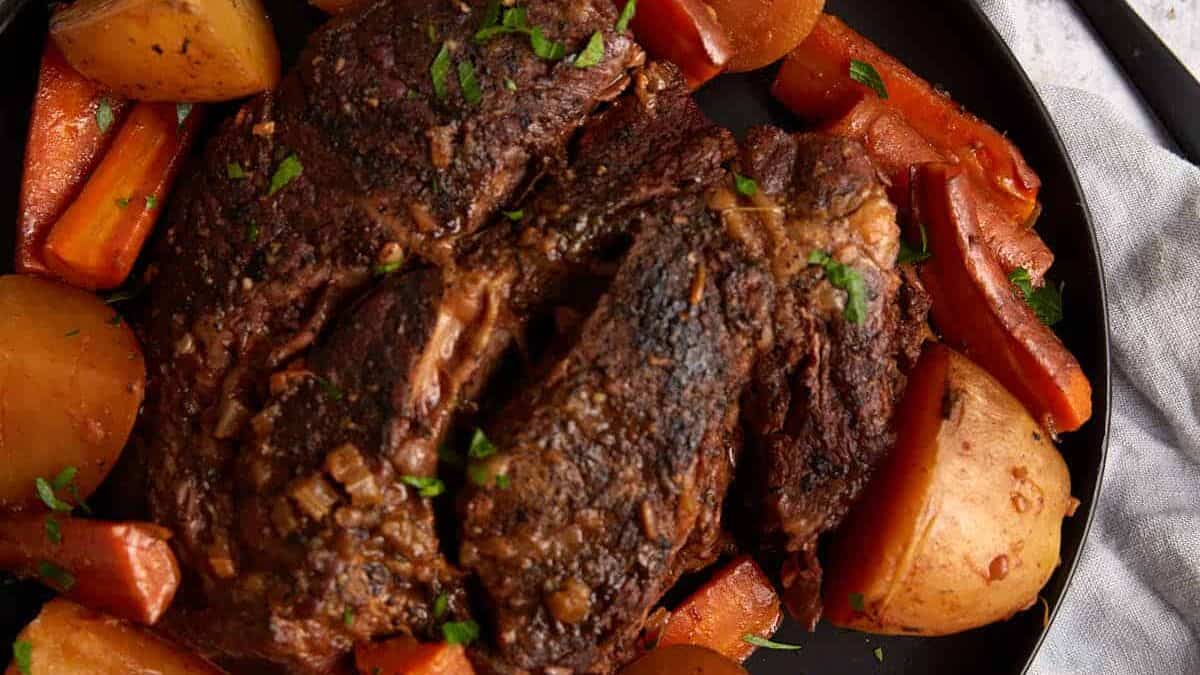 A platter of roast beef with carrots and potatoes.
