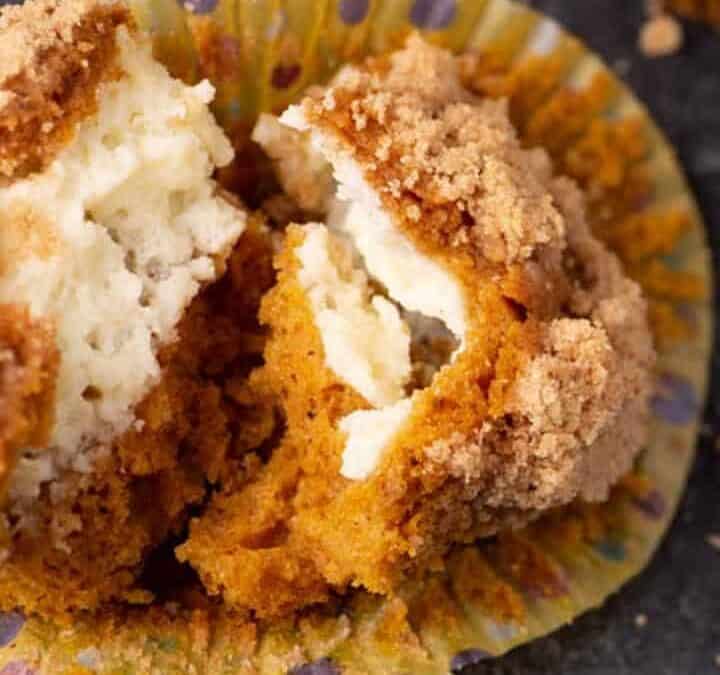 A pumpkin muffin cut in half with cream cheese filling