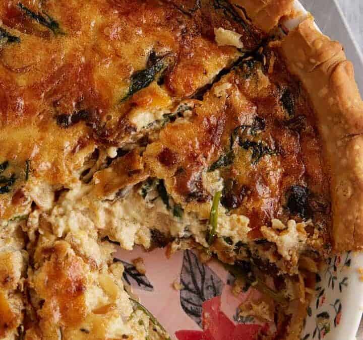 A baked quiche next to a pie server.