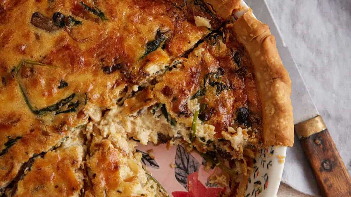 A baked quiche next to a pie server.